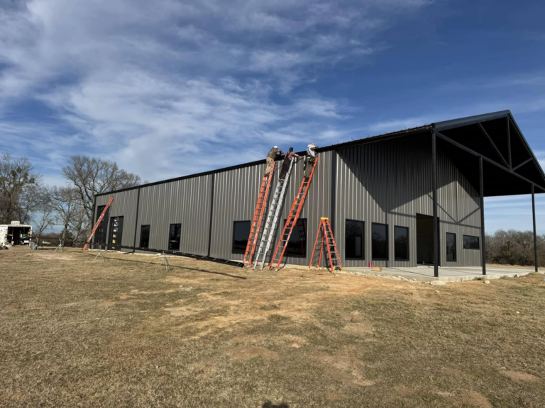gutter-repair-working-on-metal-building-with-ladders-and-sky